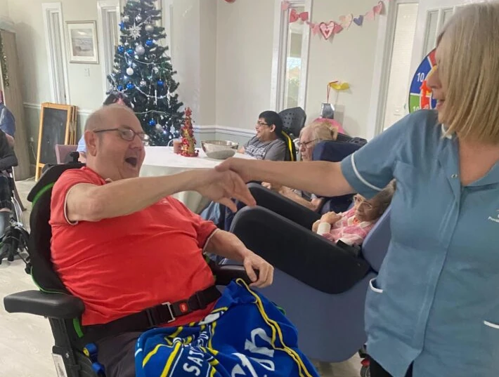 A man in a wheelchair dancing with a carer
