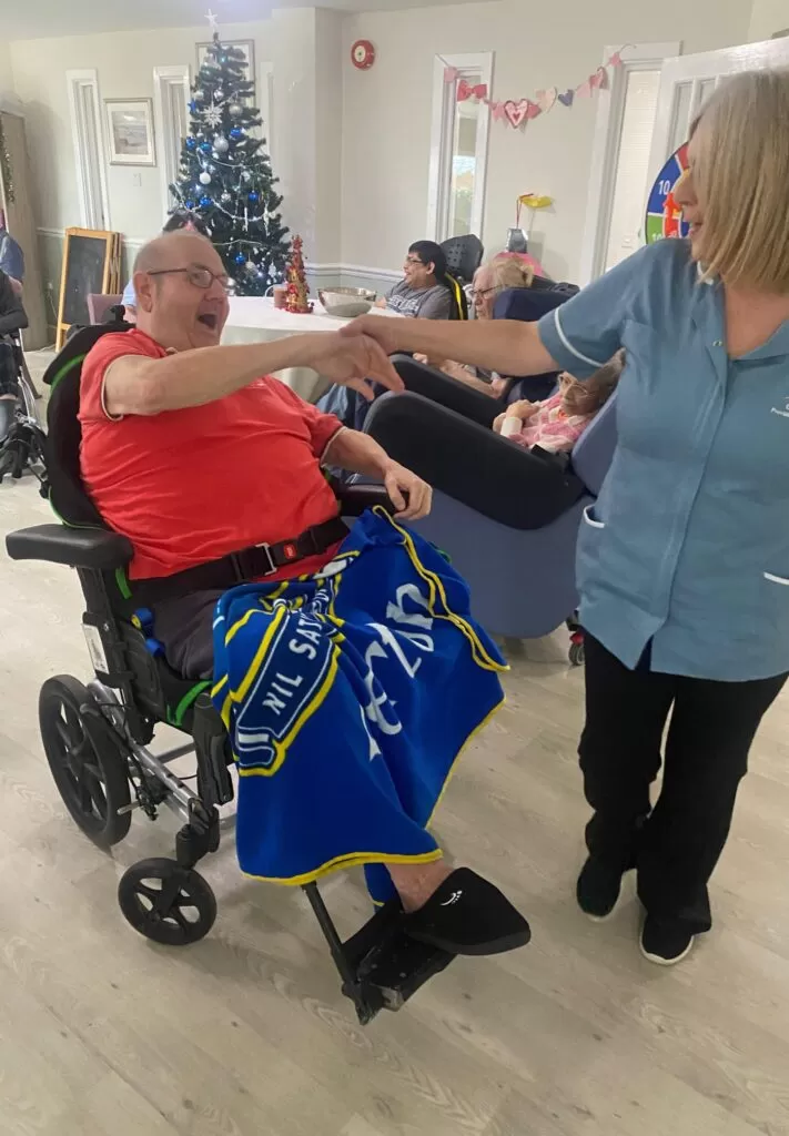 A man in a wheelchair dancing with a carer